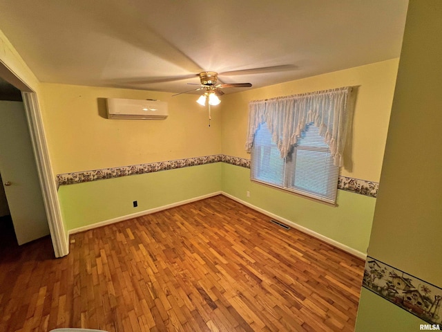 empty room featuring a wall mounted air conditioner, hardwood / wood-style flooring, and ceiling fan