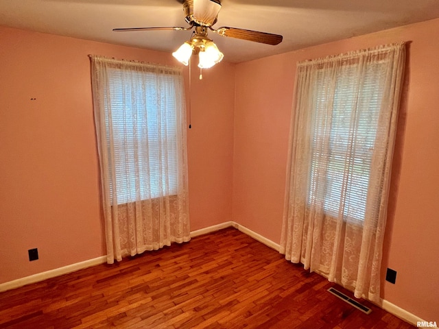 empty room with ceiling fan, plenty of natural light, and hardwood / wood-style floors