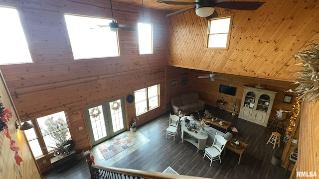 unfurnished living room with dark wood-type flooring, high vaulted ceiling, and wooden walls