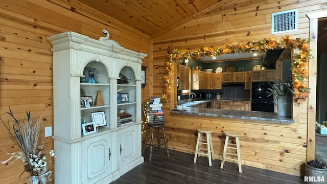 kitchen featuring kitchen peninsula, wood walls, vaulted ceiling, and dark hardwood / wood-style flooring