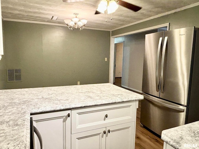 kitchen featuring stainless steel refrigerator, ceiling fan, wood-type flooring, crown molding, and white cabinetry