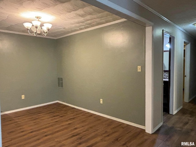 spare room featuring a notable chandelier, crown molding, and dark hardwood / wood-style flooring