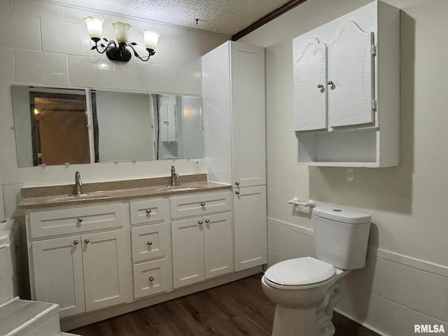 bathroom with a textured ceiling, hardwood / wood-style flooring, vanity, and toilet