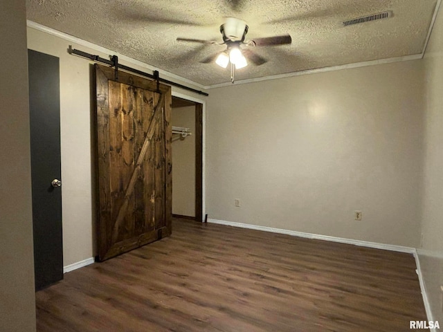 empty room featuring ceiling fan, a textured ceiling, and a barn door