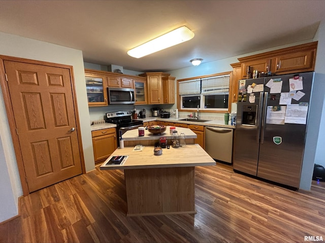 kitchen with wooden counters, a kitchen island, stainless steel appliances, sink, and dark hardwood / wood-style flooring