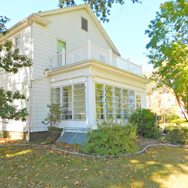 view of side of property featuring a yard and a balcony