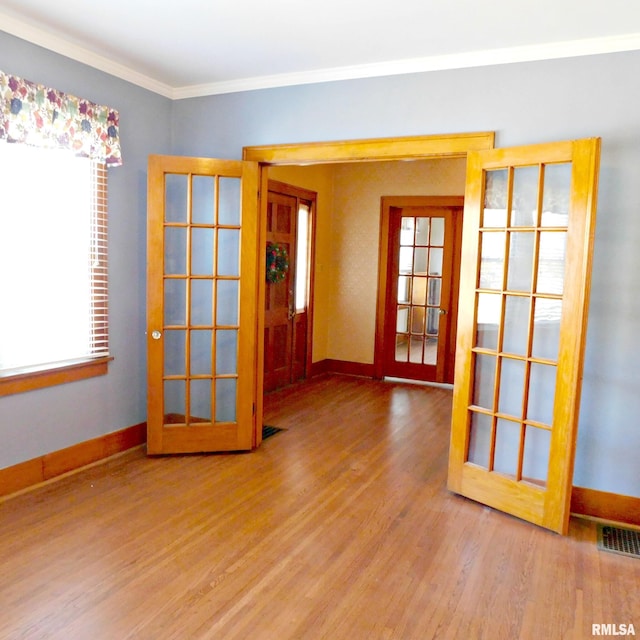 spare room featuring crown molding, wood-type flooring, and french doors