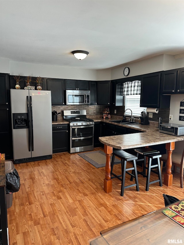 kitchen featuring sink, decorative backsplash, stainless steel appliances, and light hardwood / wood-style floors