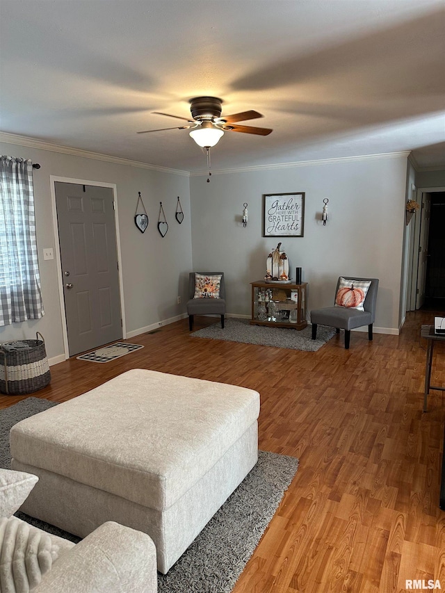 living room with ornamental molding, wood-type flooring, and ceiling fan