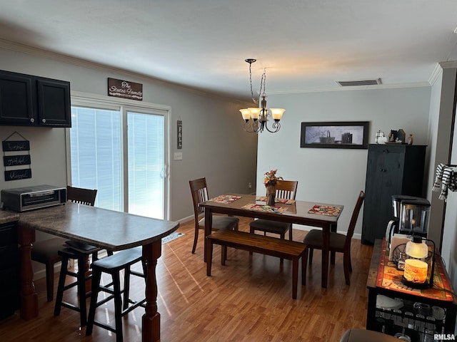 dining area with crown molding, hardwood / wood-style flooring, and an inviting chandelier