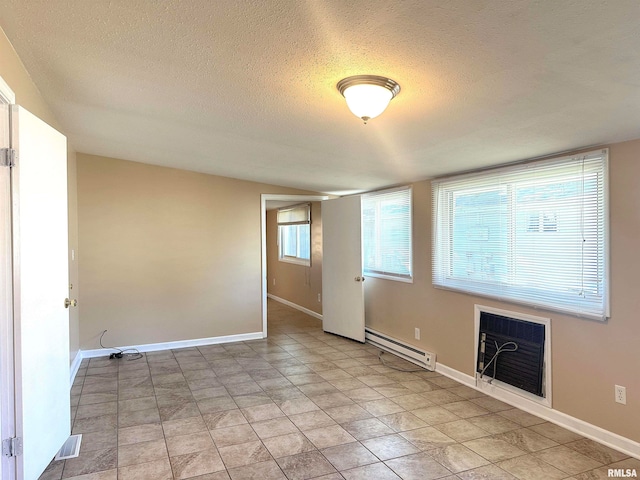 tiled empty room with a textured ceiling and a baseboard radiator