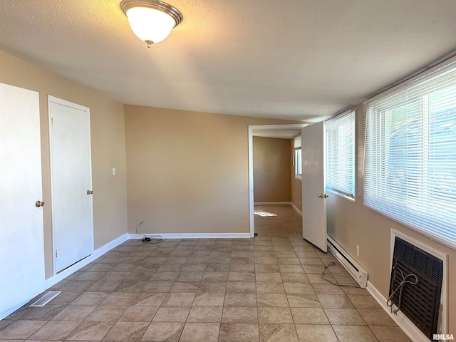 spare room featuring light tile patterned floors, a textured ceiling, and a baseboard radiator