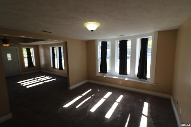 carpeted empty room featuring a textured ceiling