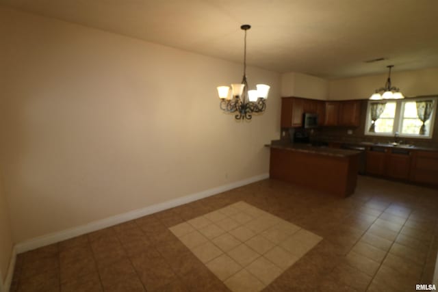 kitchen featuring dark tile patterned flooring, sink, kitchen peninsula, pendant lighting, and a chandelier