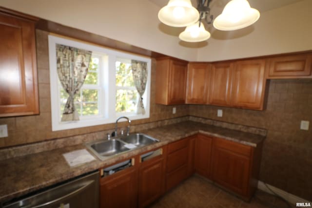 kitchen featuring tasteful backsplash, sink, dark tile patterned floors, dark stone counters, and stainless steel dishwasher