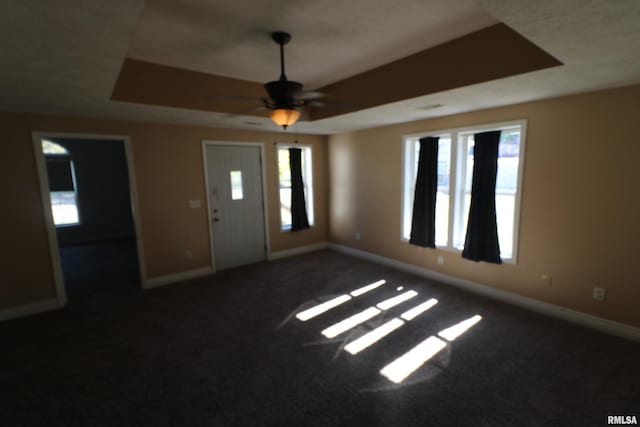 carpeted foyer with a raised ceiling and ceiling fan