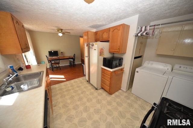 kitchen featuring a textured ceiling, ceiling fan, sink, washer and dryer, and white fridge