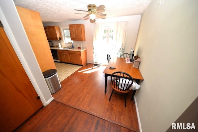 dining area with ceiling fan, light hardwood / wood-style floors, sink, and a textured ceiling