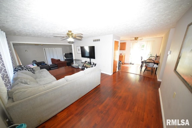 living room with ceiling fan, a textured ceiling, and hardwood / wood-style flooring