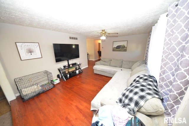 living room featuring ceiling fan, a textured ceiling, and hardwood / wood-style flooring