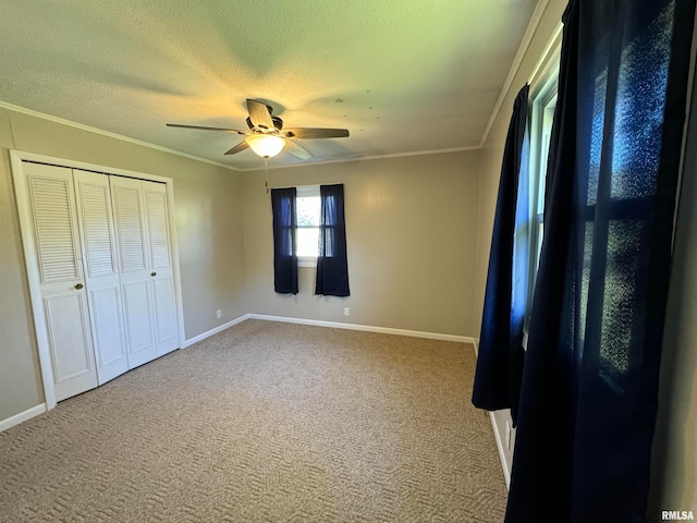 unfurnished bedroom featuring ceiling fan, a textured ceiling, carpet floors, a closet, and crown molding