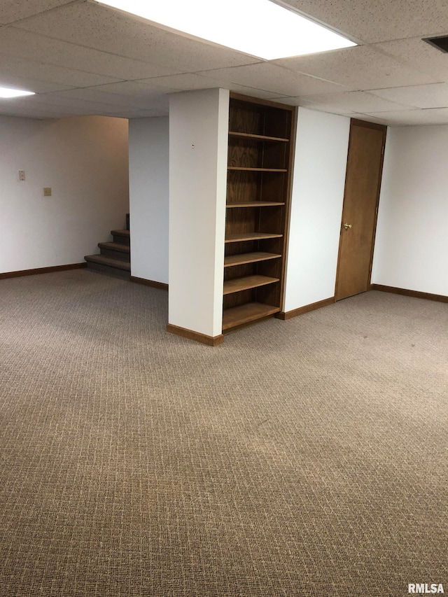 basement with carpet, a drop ceiling, and built in shelves