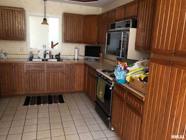 kitchen featuring black range, oven, sink, hanging light fixtures, and light tile patterned floors