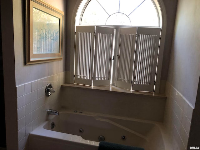 bathroom with a wealth of natural light, tile walls, and a tub to relax in