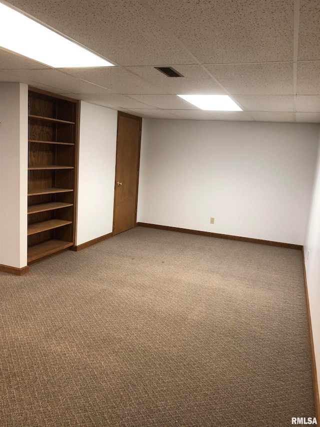 basement featuring a drop ceiling, carpet flooring, and built in features