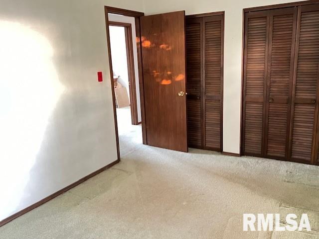 unfurnished bedroom featuring two closets and light colored carpet