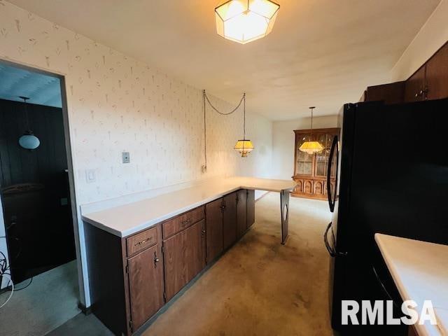 kitchen featuring light carpet, dark brown cabinetry, pendant lighting, and black fridge