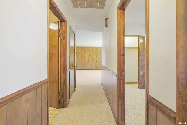 hall with light colored carpet and wooden walls