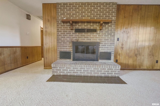 carpeted living room with wooden walls and a fireplace