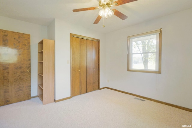 unfurnished bedroom featuring a closet, light colored carpet, and ceiling fan