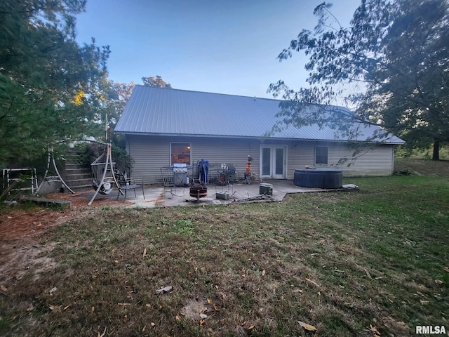 rear view of property featuring french doors, a patio, and a lawn