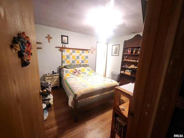 bedroom with a textured ceiling and hardwood / wood-style flooring