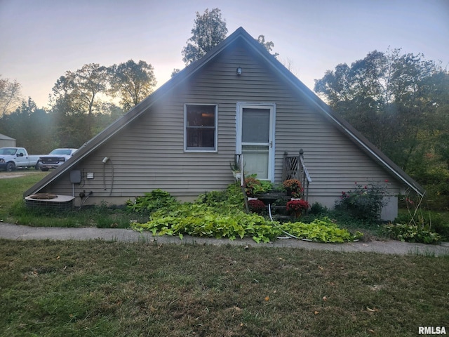 property exterior at dusk featuring a lawn