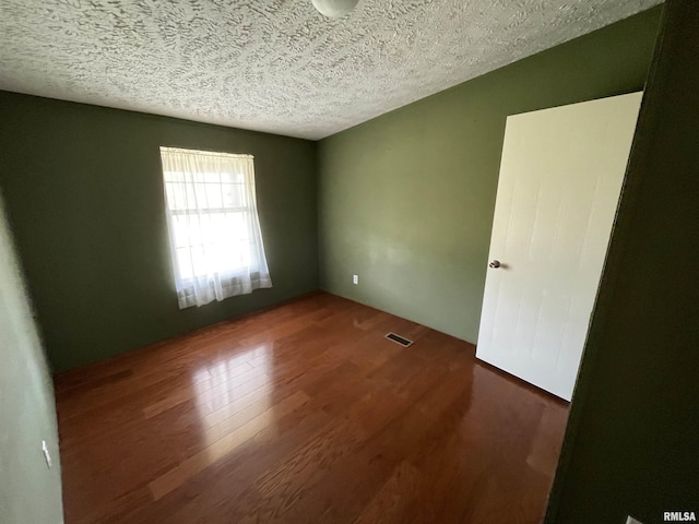 spare room with a textured ceiling and dark wood-type flooring