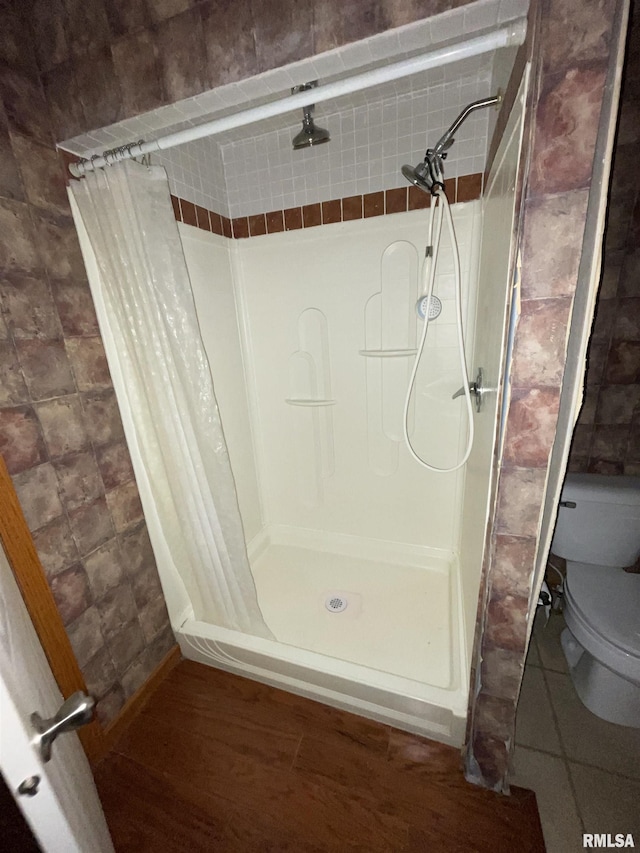 bathroom featuring tile patterned floors, toilet, and walk in shower