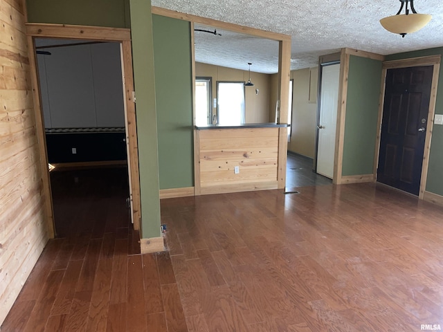 spare room featuring wood walls, wood-type flooring, and a textured ceiling