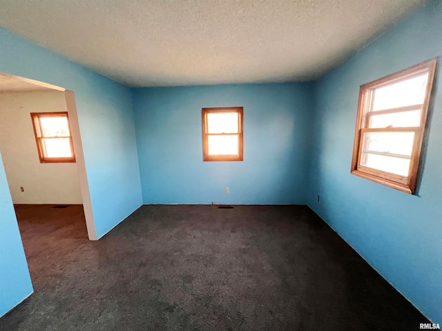 empty room featuring dark colored carpet and a textured ceiling