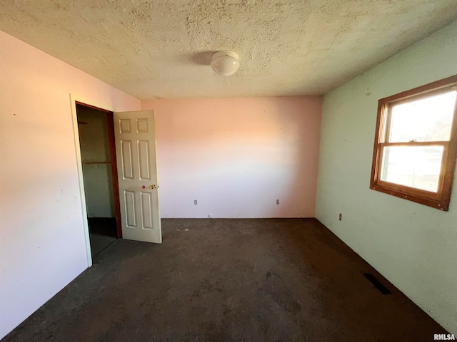 spare room with dark carpet and a textured ceiling