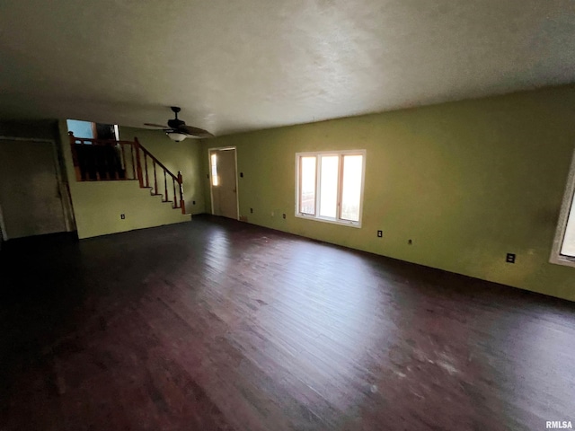 unfurnished living room featuring ceiling fan and dark wood-type flooring