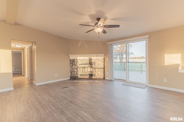 unfurnished living room featuring ceiling fan, light hardwood / wood-style flooring, vaulted ceiling with beams, and a fireplace