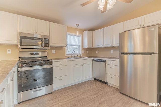 kitchen with lofted ceiling, appliances with stainless steel finishes, light wood-type flooring, and white cabinetry