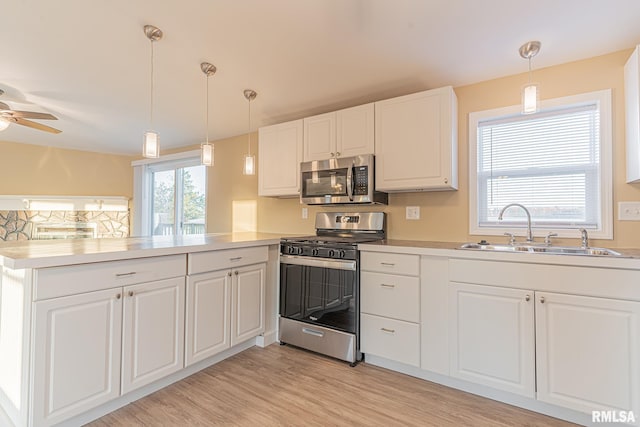 kitchen with appliances with stainless steel finishes, kitchen peninsula, light hardwood / wood-style floors, pendant lighting, and white cabinets