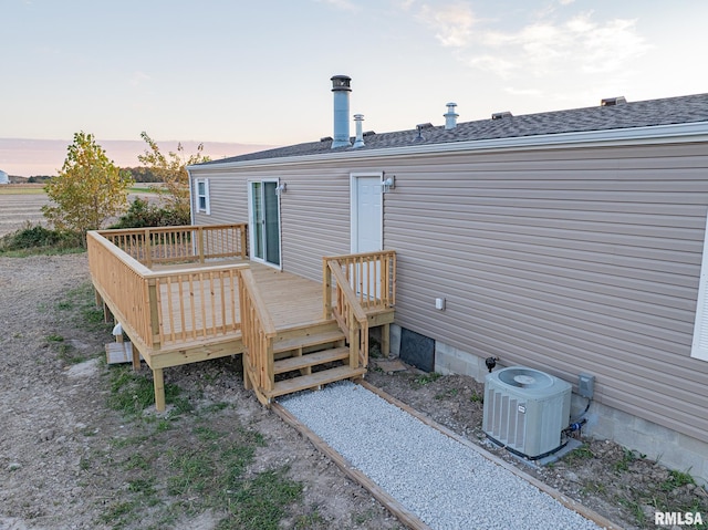 back house at dusk featuring cooling unit and a wooden deck