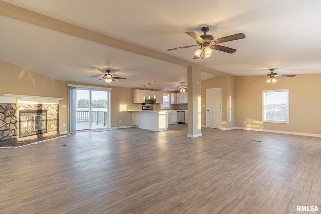 unfurnished living room with a stone fireplace, vaulted ceiling, and hardwood / wood-style floors