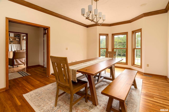 dining room featuring a notable chandelier, hardwood / wood-style flooring, and crown molding