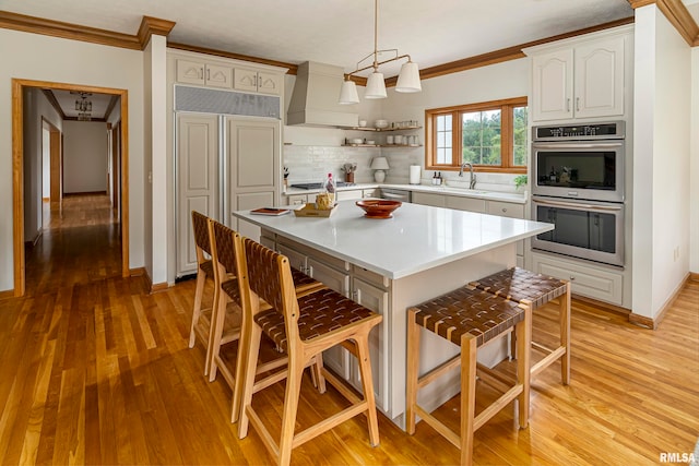 kitchen featuring a kitchen island, decorative backsplash, stainless steel appliances, pendant lighting, and premium range hood